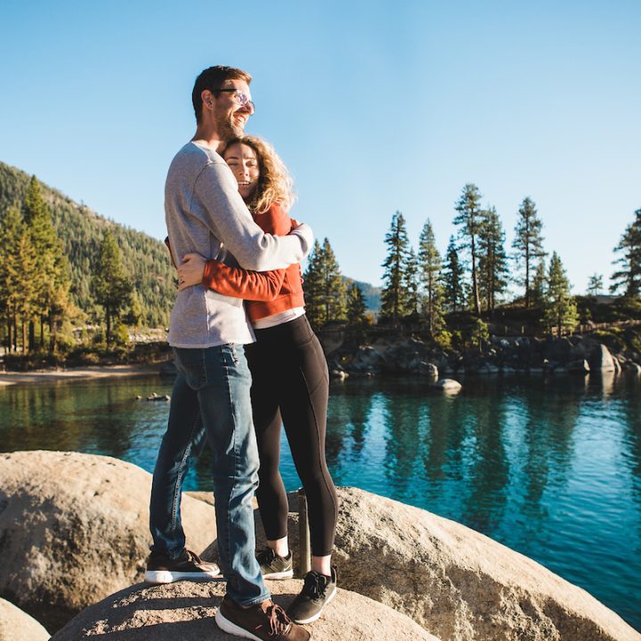 Couple hugging on rocks enjoying Sand Harbor overlooking Lake Tahoe