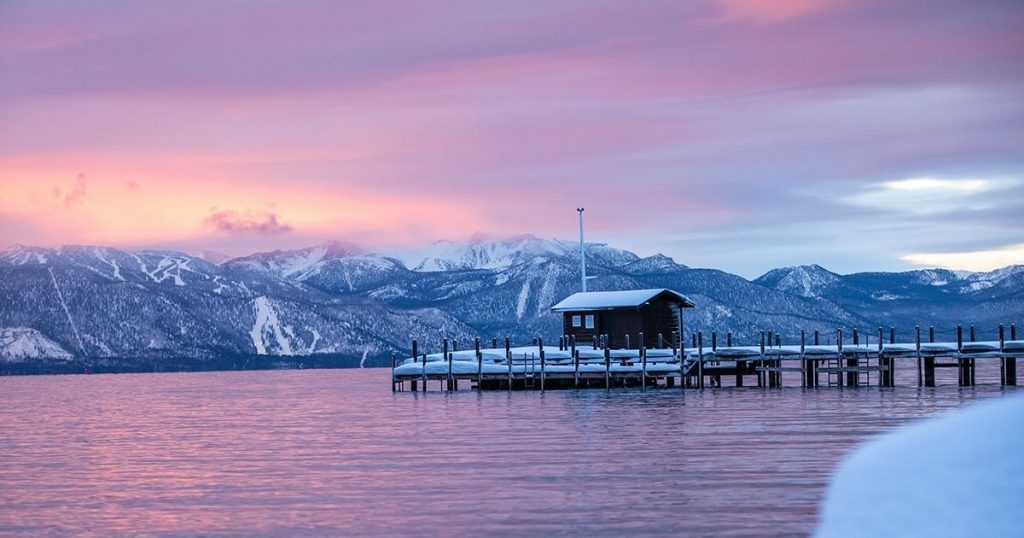 An early evening shot of a snowy Squaw Valley shore with beautiful mountains in the distance and lilac skies.