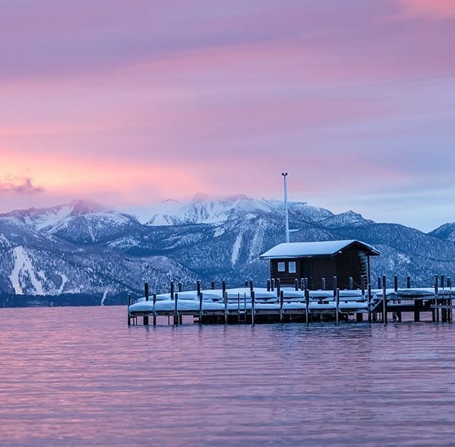 An early evening shot of a snowy Squaw Valley shore with beautiful mountains in the distance and lilac skies.