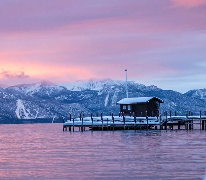 An early evening shot of a snowy Squaw Valley shore with beautiful mountains in the distance and lilac skies.