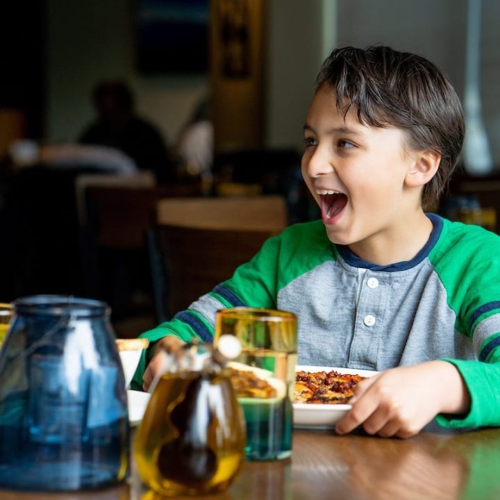 A child dines happily on pizza in a cozy setting.