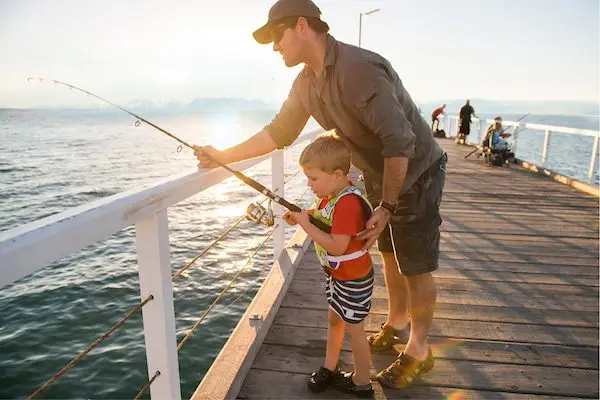 Father helping son on pier fishing Lake Tahoe