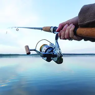 Lake Tahoe shore fishing with close-up of hand holding rod