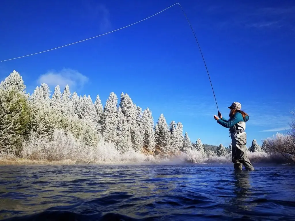 Fly fishing in Lake Tahoe with snow trees behind